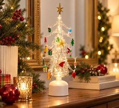 Pino Twist natalizio in vetro EDG H45 cm con decori multicolor e luci LED, ambientato su una consolle decorata per Natale in un elegante soggiorno.
